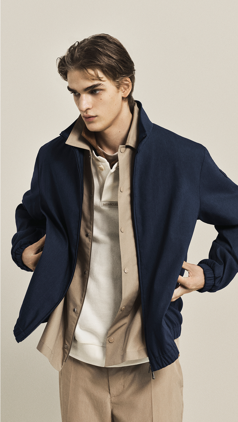 Moncler Spring/Summer ; collection homme et femme : veste bleu marine sur chemise beige et polo blanc.