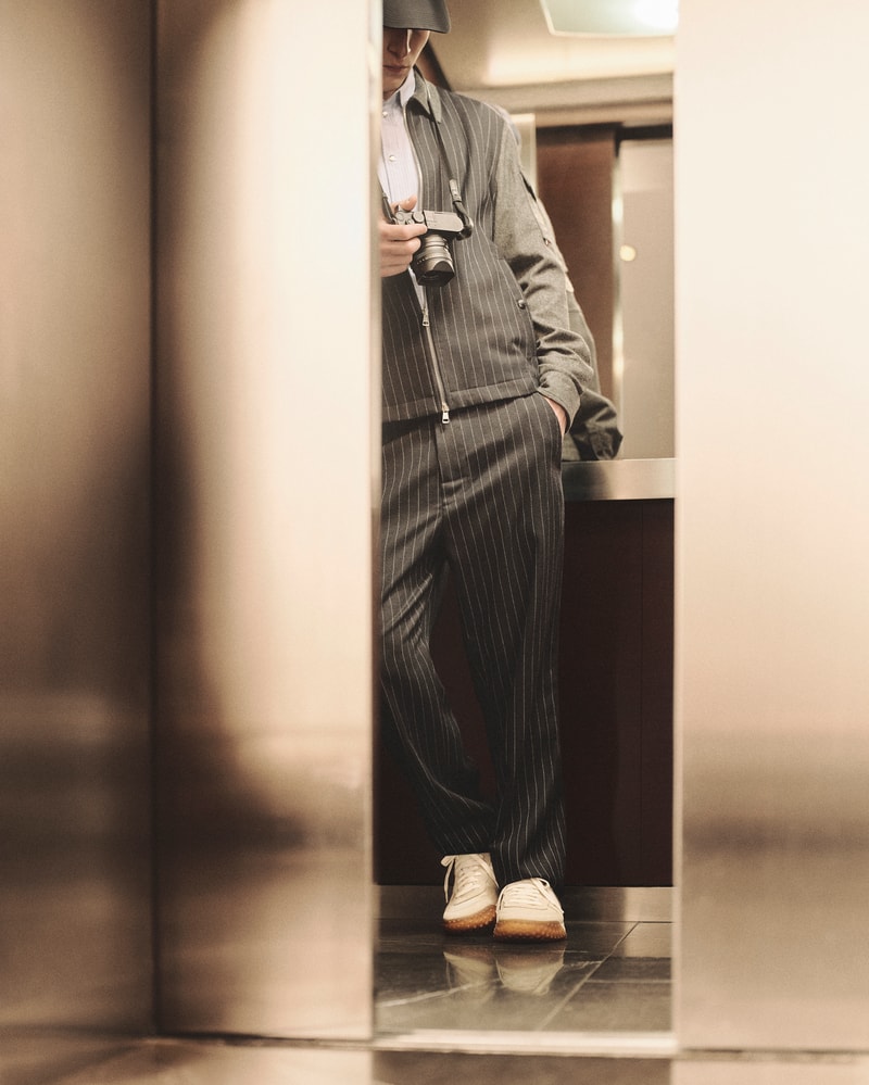 Moncler CityTrek: white and beige sneakers with rubber sole and pinstripe trousers.