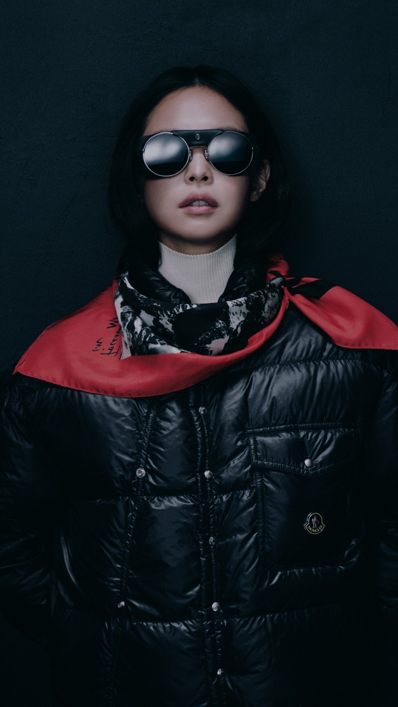 Moncler Re/Icons 2026, Pioneers in Moncler: Jennie in sunglasses, a glossy black down jacket and a red printed scarf.