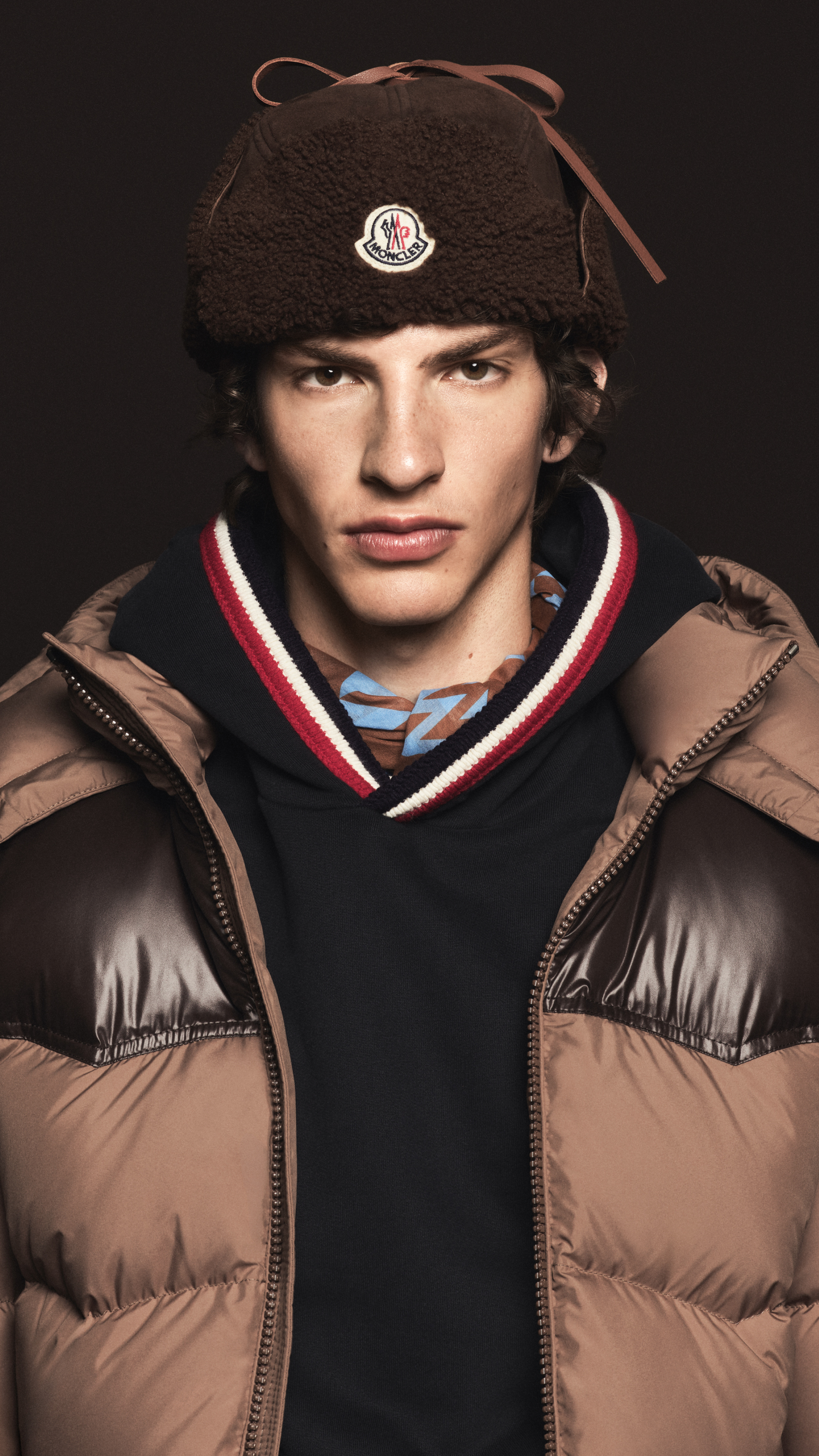 Moncler new in for men. Brown shearling hat, camel down jacket with glossy brown patch and hoodie with striped trim.