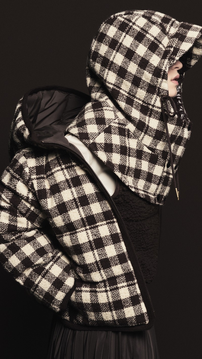 Moncler メンズ&ウィメンズアウターウェア。チェック柄ダウンジャケットと共布のフード、ブラックのプリーツスカート。