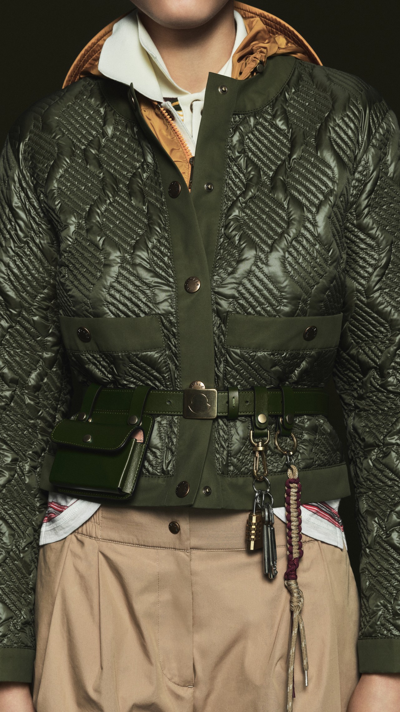 Moncler Pre-Fall 2026 : mannequin en doudoune noire brillante sur veste à fines rayures et chemise en denim