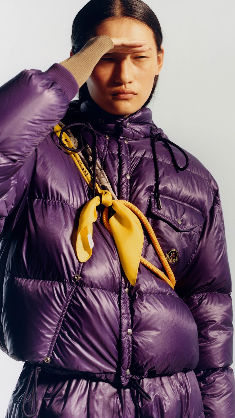 Moncler Re/Icons 2026 for men and women. Karakorum: glossy purple down jacket with yellow scarf and rope.