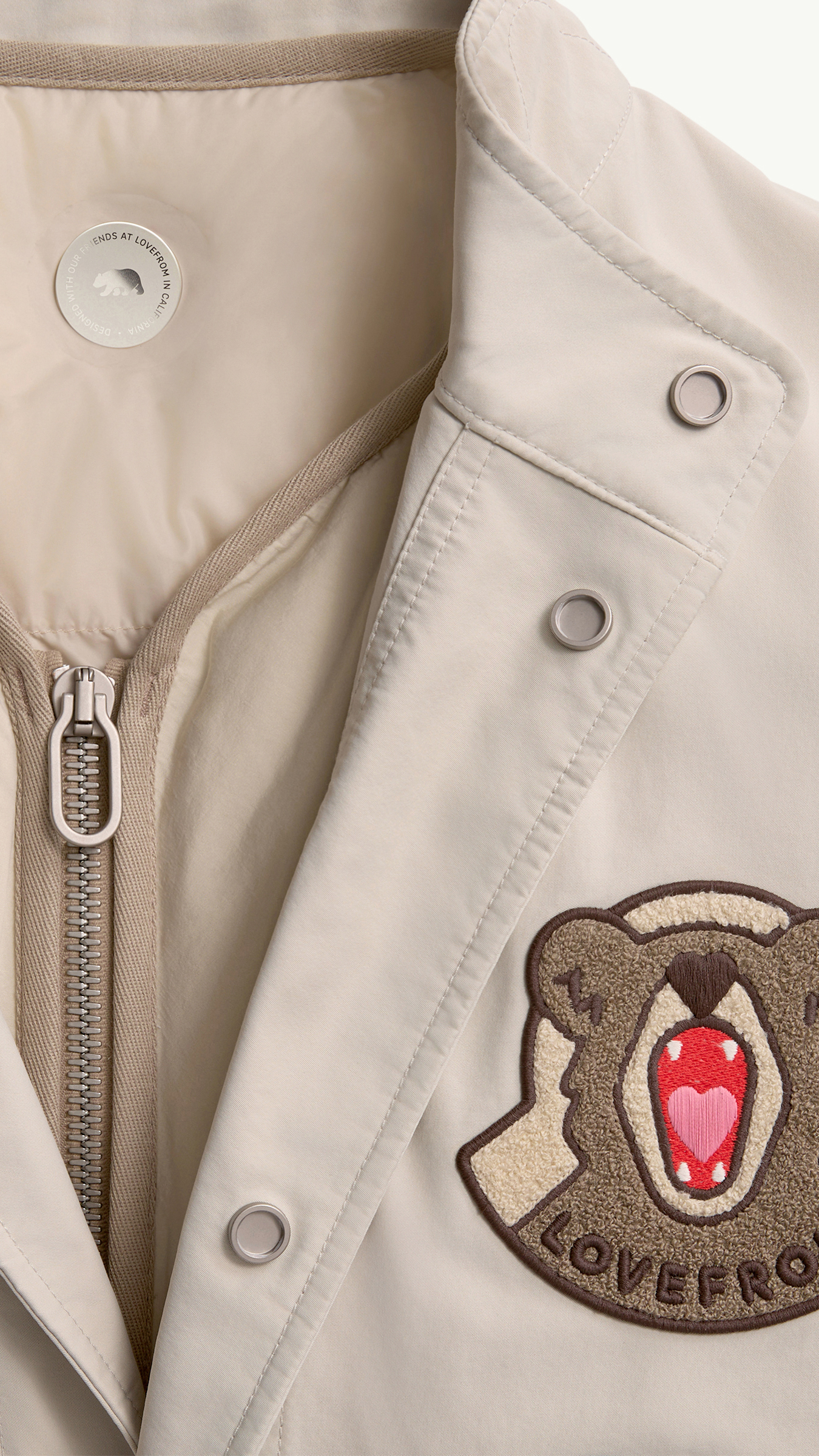 Moncler in collaboration with Jony Ive. The LoveFrom brown and cream bear logo on beige fabric.