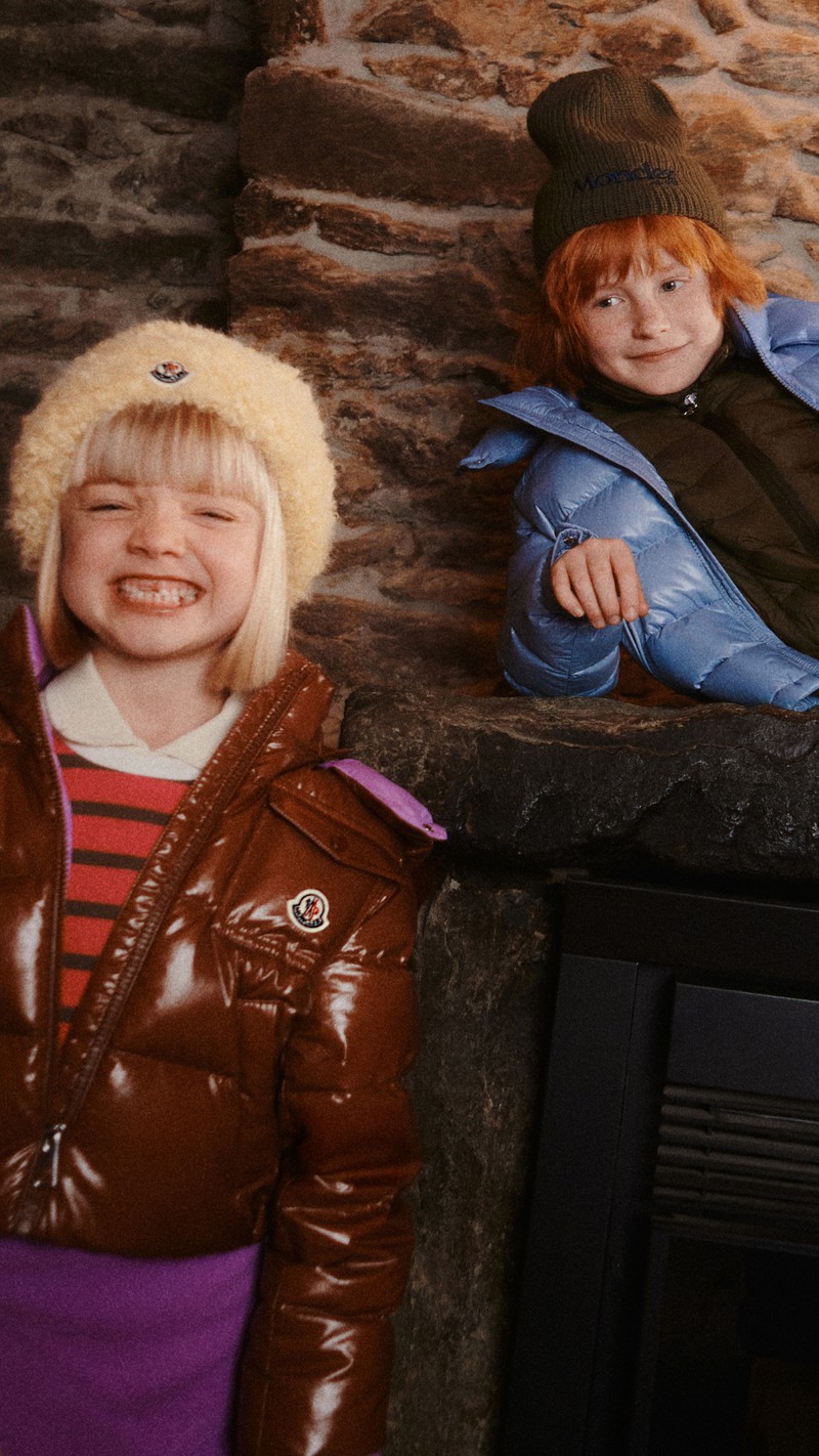 Moncler pour garçon et fille : doudoune marron, bonnet beige, pull rayé ; bonnet et sweat vert, doudoune bleue, jean.
