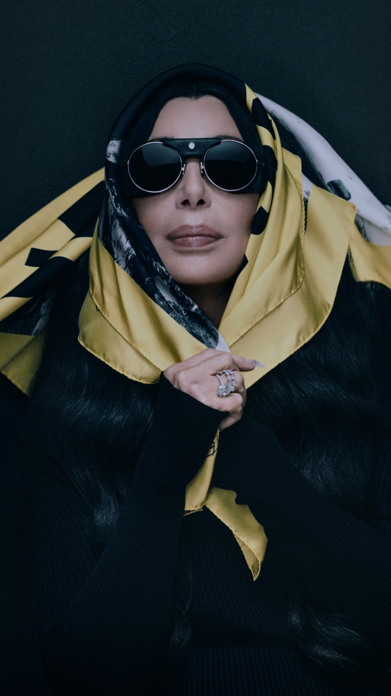 Moncler Re/Icons 2026, Pioneers in Moncler: Cher in round sunglasses wrapped in a yellow and black printed silk scarf.