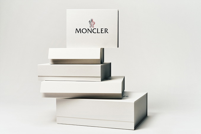 Stack of white Moncler shipping boxes of different sizes on a light background.