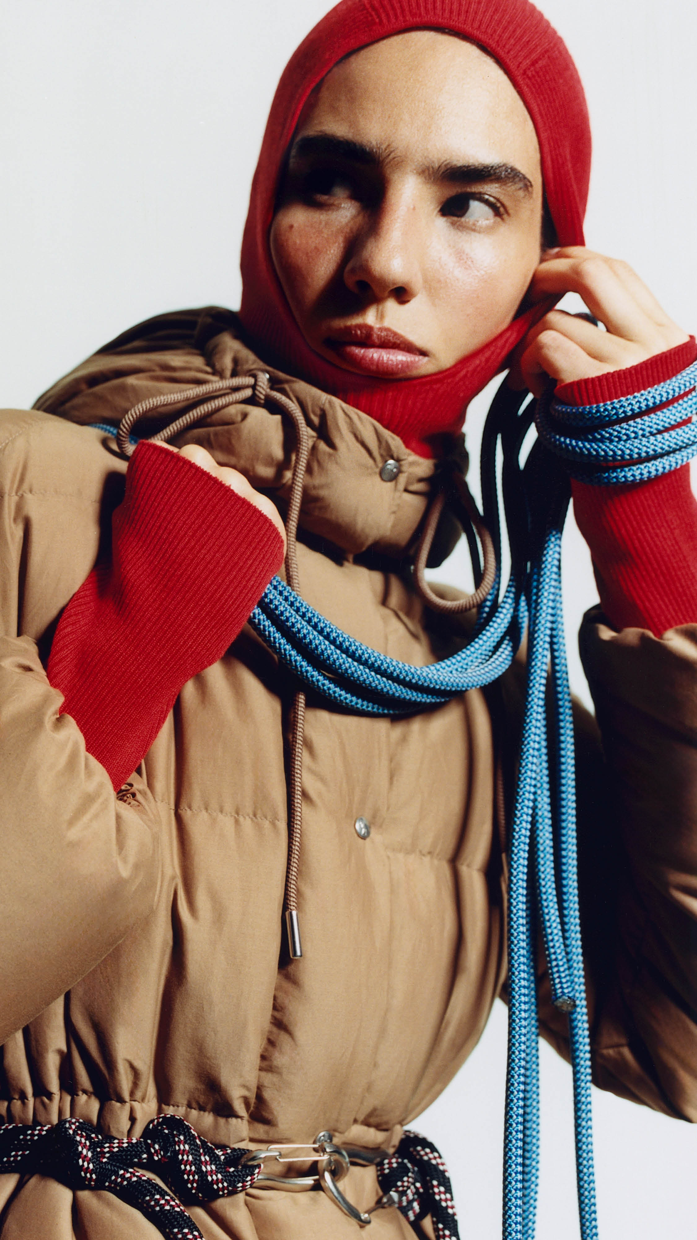 Moncler Re/Icons 2026 for men and women. Karakorum: glossy purple down jacket with yellow scarf and rope.