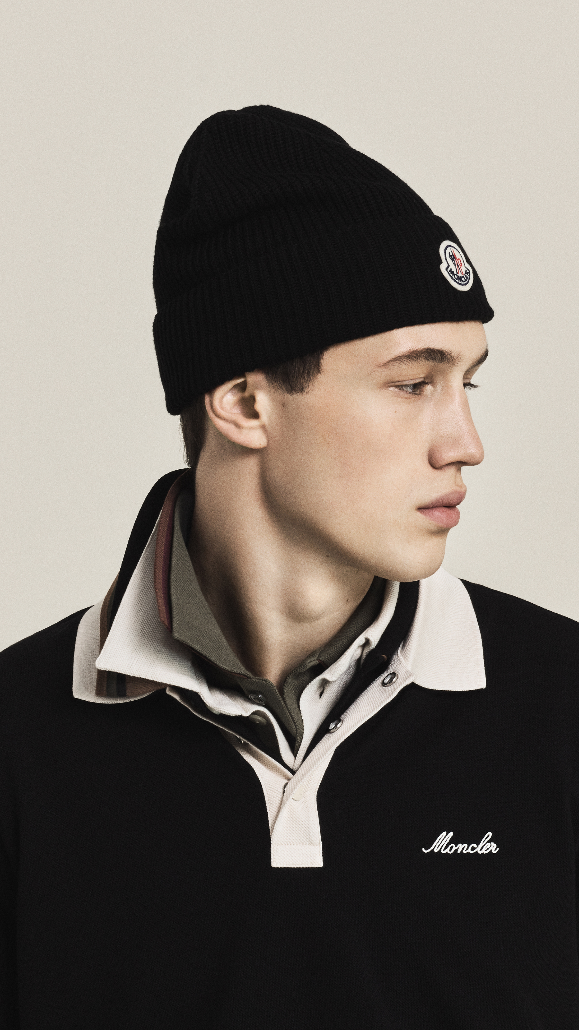 Moncler Spring/Summer; men's and women's collection: navy jacket layered over a beige shirt and white polo.