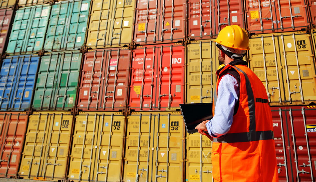 Dock yard worker in front of shipping containers